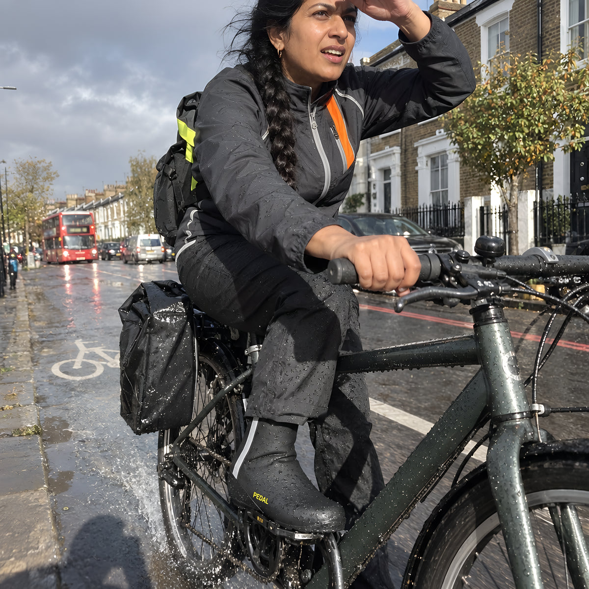 Close on PEDAL Shoe Covers pulled over a pair of sneakers on the pedals, water running off them, wet road below.